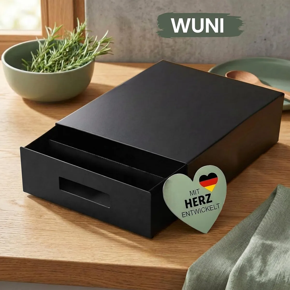 WUNI Air Fryer Box aus matt schwarzem Stahl auf einer Eichen-Arbeitsplatte mit Kräuterschale und Herz-Anhänger